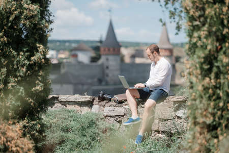 Young successful man working on laptop outdoor in cityの写真素材