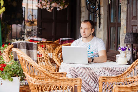Happy young man in caffee. He works on his laptop to get all his business done early in the morningの写真素材