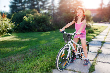 happy child girl riding bicycle in summer sunset in the park. Active kidsの写真素材