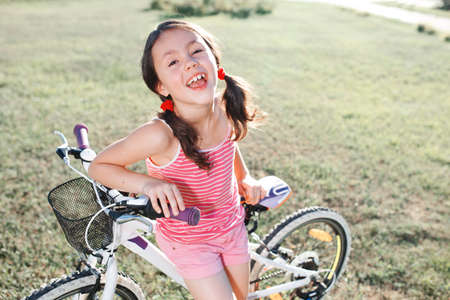 happy child girl riding bicycle in summer sunset in the park. Active kidsの写真素材