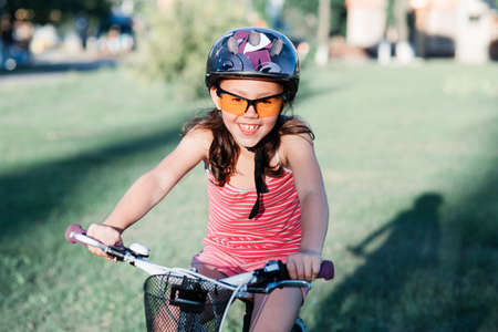 happy child girl riding bicycle in summer sunset in the park. Active kidsの写真素材