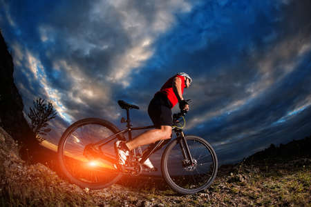 mountain bicycle rider on the hill with sunrise and cloudy sky backgroundの写真素材