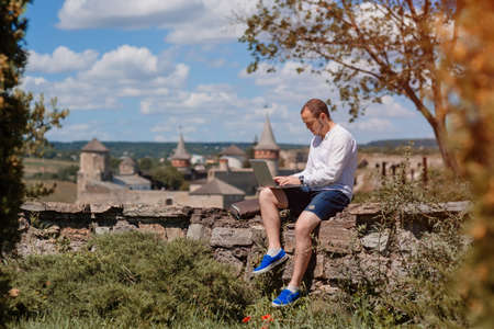Attractive man working in your home garden. Young man working talking with smart phone in outdoors.の写真素材