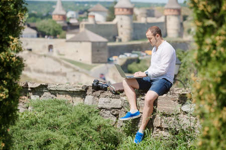 Attractive man working in your home garden. Young man working talking with smart phone in outdoors.