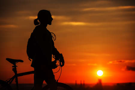 Silhouette of a bike on sky background on red sunsetの写真素材