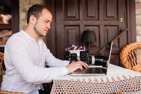 Man is looking at laptop with excitement. Photographer is choosing photos from a shootの写真素材