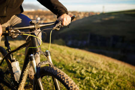 Closeup of cyclist hand on handlebar. Unrecognizable sportsman riding his bicycle on sunny spring day.の写真素材