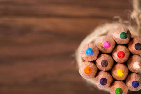 Set of sharp colorful pencils tied with wool rope stand on a wooden blank boardの写真素材