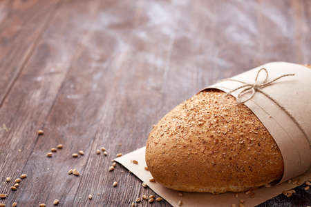 White bread in the baking paper and decorative rope on the wooden table, selective focus. Brown background. Table with flour and whole. Natural products and materials. Baker and tasty.の写真素材