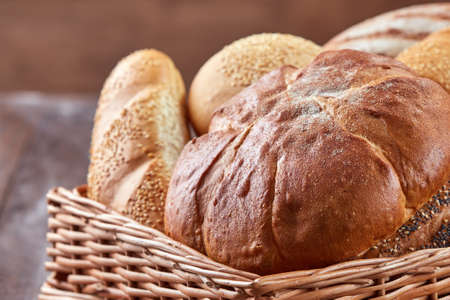Different kinds of Bread in a wicker basket on a wooden background.の写真素材