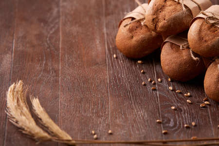 different bread on the wooden table, wheat, paper bags, rope, ears of wheatの写真素材