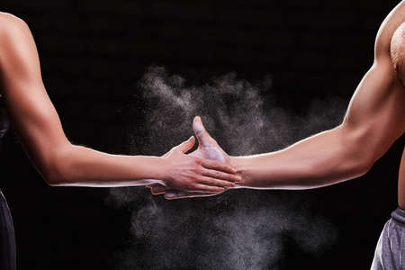 Cropped image of hands of a young couple on dark background. Crossfit fitness, bodybuilding conceptの写真素材