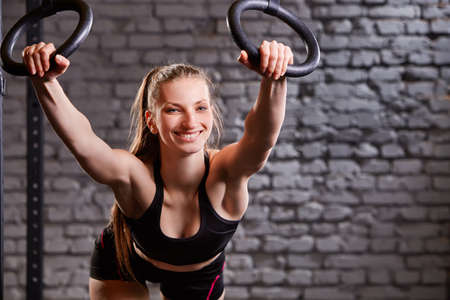 Workout on crossfit rings. Fitness woman workout on the TRX in the gym.の写真素材