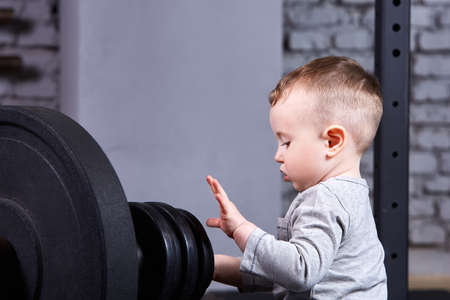 Close-up photo of little boy with barbell against brick wall in the cross fit gym.の写真素材