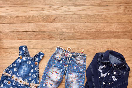 Childrens jeans, jacket and denim dress on wooden background.の写真素材