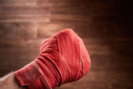 Close up image of fist of a boxer with red bandage against brown background.の写真素材