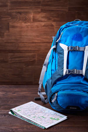 Tourist blue big backpack and map against wooden background.の写真素材