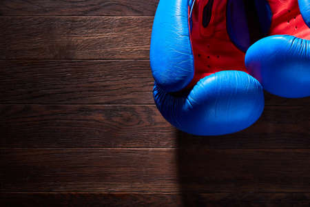 Close-up of a pair of boxing blue and red gloves hanging on the wooden wall.の写真素材