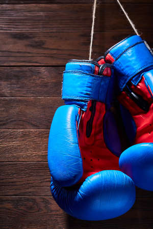 Blue and red boxing gloves hanging on wooden wall.の写真素材