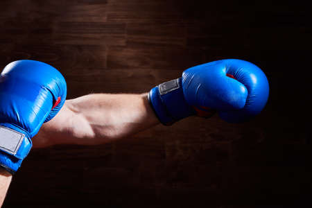 Close-up image of hands with blue and red gloves against wooden wall.の写真素材
