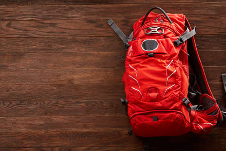 Top view of the bright orange travel backpack on a wooden background.の写真素材