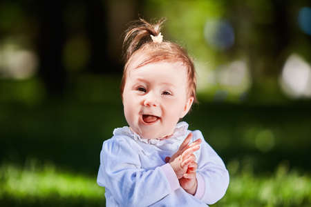 Close-up summer portrait of beautiful baby girl on the lawn in the park.の写真素材