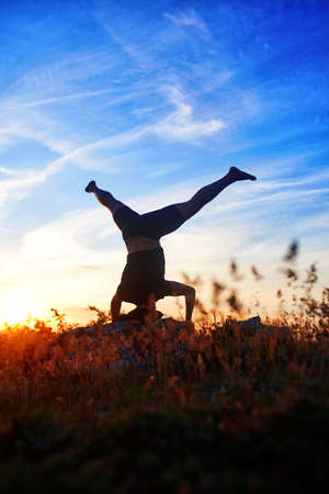 Young man practicing yoga and stretching on a rock at sunset light.の写真素材