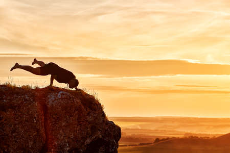 Silhouette of man doing yoga meditation against beautiful sky with clouds.の写真素材
