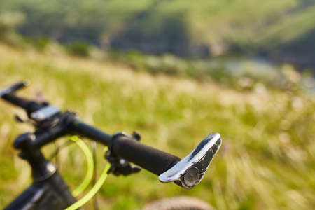 Close-up of helm of the mountain bicycle in the green grass against beautiful landscape. Detail of...