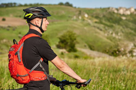 Close-up of the cyclist standing on the hill on a background with beautiful landscape.の写真素材