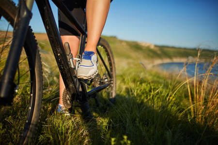 Legs of a woman in sneakers with a bicycle close upの写真素材