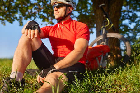 Traveler cyclist have a rest under oak tree with his bike behind him on summer afternoon.の写真素材