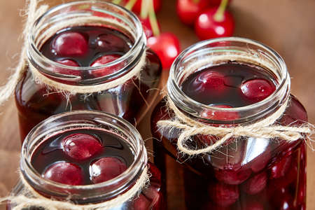 Cherry jam on wooden background in the jarsの写真素材