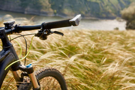Close-up of the handlaber of mountain bicycle against beautiful landscape in summer season.の写真素材