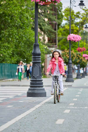 Cute kid girl in blue helmet going to ride her bikeの写真素材