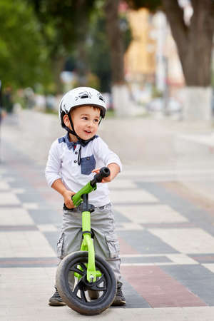 Little boy kid in helmet ride a bike in city park. Cheerful child outdoor.の写真素材