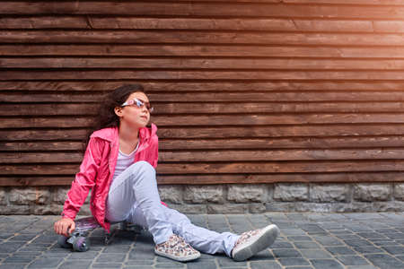 Stylish little girl child wearing a summer or autumn pink jacket, white jeans, sunglassesの写真素材