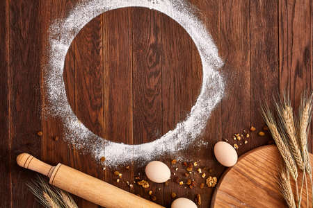 top view eggs, dough, flour and rolling-pin on wooden tableの写真素材