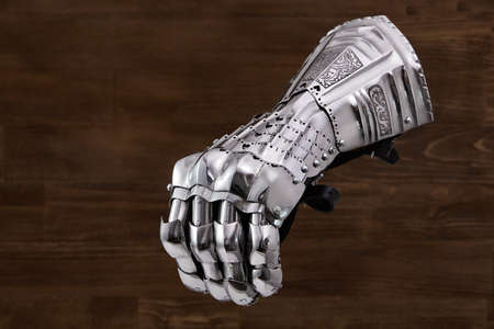 Medieval armor, detail of an ancient armor. Steel gloves on wooden background.