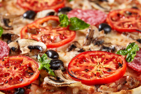 Closeup of pizza with salami, tomatoes and olivesの写真素材