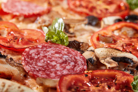 Closeup of pizza with salami, tomatoes and olivesの写真素材