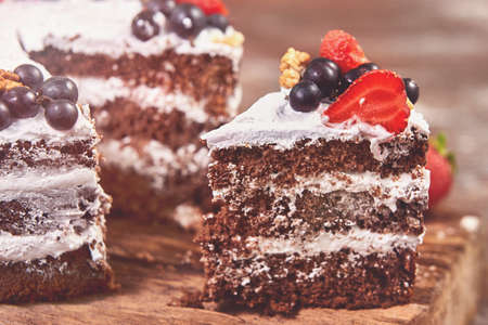 a cut of cake with whipped cream and strawberry fruits on wood table backgroundの写真素材