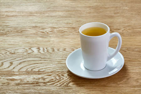 Cup of mint tea and green leaves on light tableの写真素材