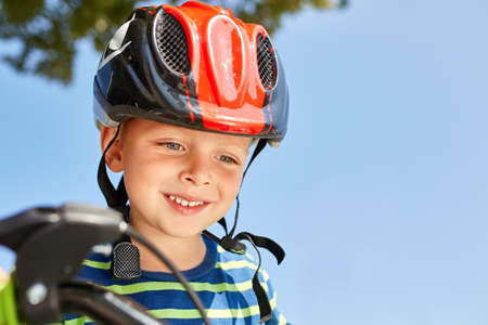 Boy in helmet standing with bike at autumn parkの写真素材