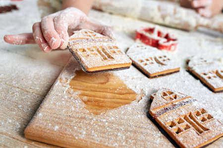 Childs hands decorate traditional Christmas cookies.
