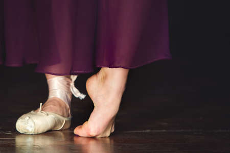 Elegant ballerina is posing in the studio on the dark background in low key