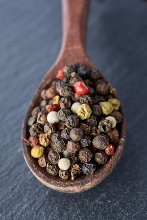 Chinese pepper, Sichuan pepper in wooden spoon on black slate stone plate with copy space