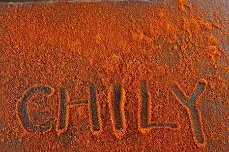 Top view on the texture background of red chilli pepper powder with text isolated on dark backgroundの写真素材