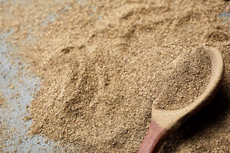 Closeup black pepper whole in wooden spoon on black stone table