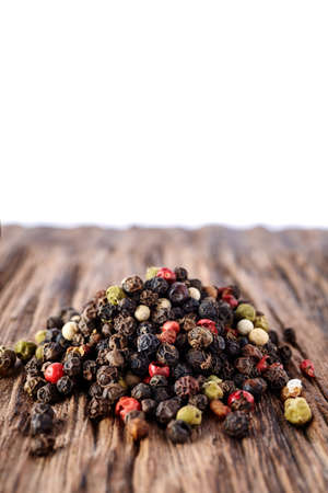 Black, red and white peppercorns isolated on wooden background, shallow depth of field.の写真素材
